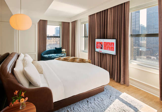 Elegant penthouse bedroom at Virgin Hotels with luxury bedding, floor-to-ceiling windows, and city views.