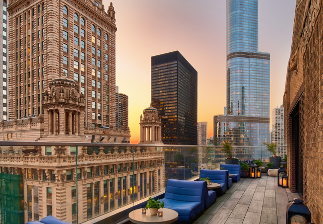 Sunset view from Virgin Hotels Chicago Cerise patio with cozy seating, string lights, and a warm ambiance.