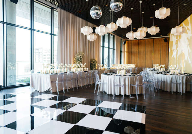 Fashionable event venue in Virgin Hotels Dallas with tables, vibrant decor, and ample natural light.