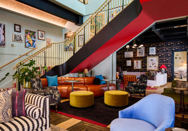 Spacious lounge area with modern decor and vibrant seating at the Commons Club in Virgin Hotels New Orleans.